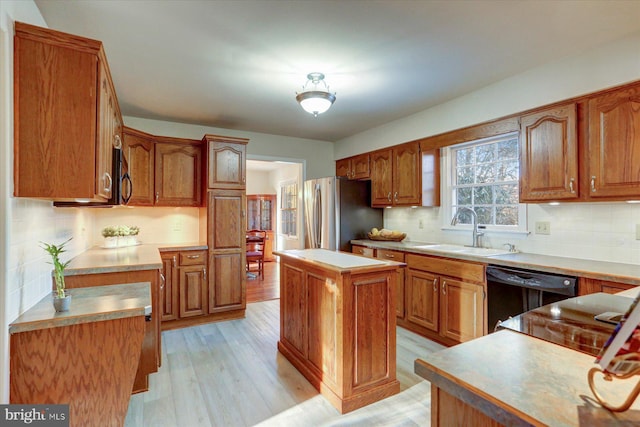 kitchen featuring a center island, backsplash, black appliances, sink, and light hardwood / wood-style flooring