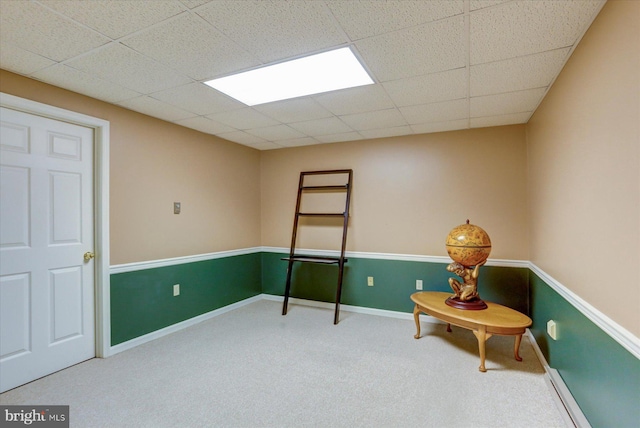 living area featuring a paneled ceiling and carpet