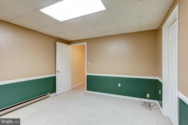 unfurnished room featuring carpet flooring and a baseboard heating unit