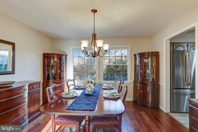 dining area with dark wood-type flooring and a notable chandelier