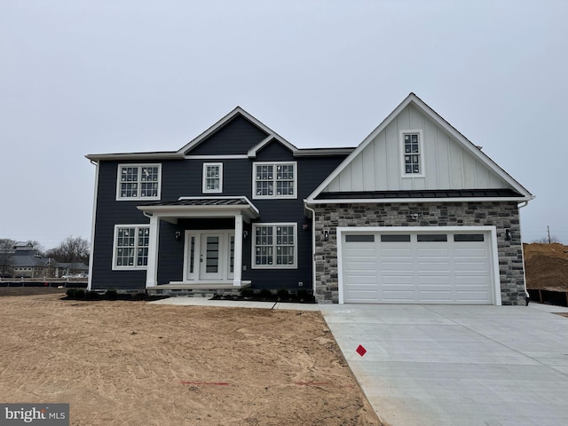 view of front of house with metal roof, a garage, driveway, board and batten siding, and a standing seam roof