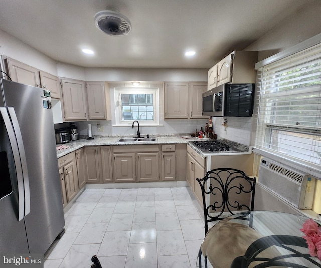 kitchen with sink, tasteful backsplash, a healthy amount of sunlight, light stone counters, and stainless steel appliances