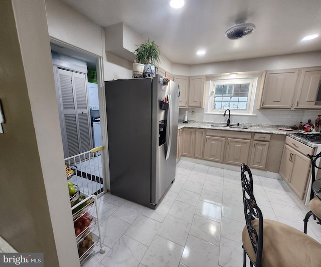 kitchen with stainless steel fridge with ice dispenser, backsplash, light brown cabinetry, and sink