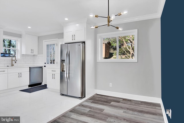 kitchen featuring ornamental molding, sink, white cabinets, and stainless steel fridge with ice dispenser