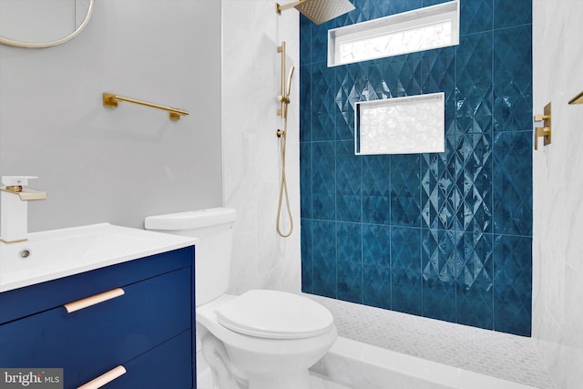 bathroom with vanity, toilet, and a tile shower