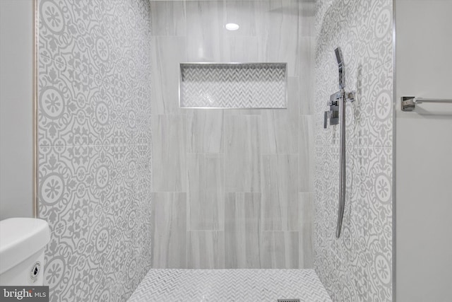 bathroom featuring a tile shower and toilet