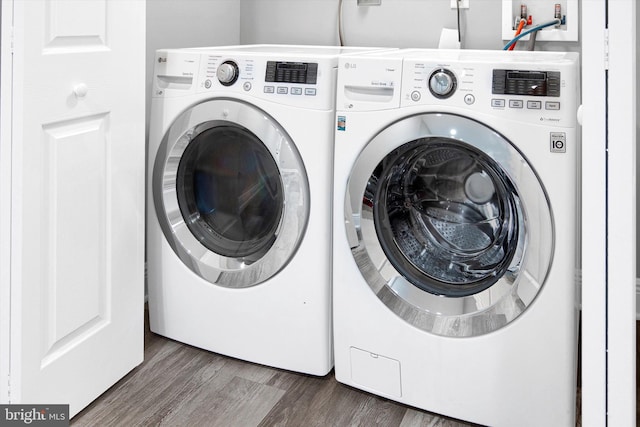 clothes washing area with laundry area, independent washer and dryer, and wood finished floors