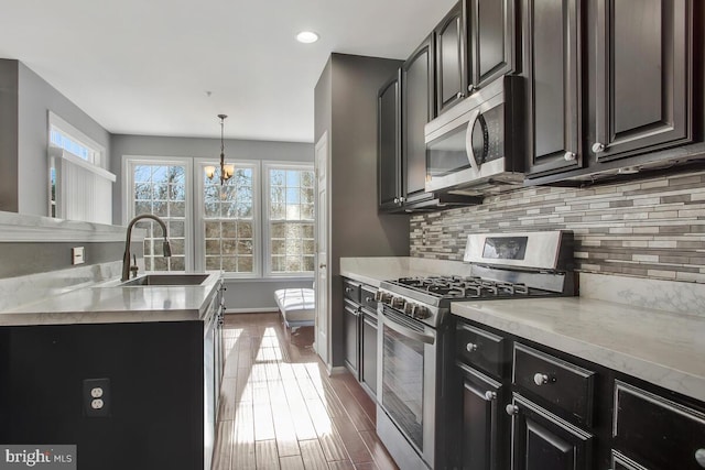 kitchen featuring sink, an inviting chandelier, backsplash, decorative light fixtures, and appliances with stainless steel finishes