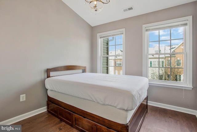 bedroom with dark hardwood / wood-style flooring, vaulted ceiling, multiple windows, and a notable chandelier