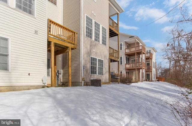 snow covered house featuring central AC unit