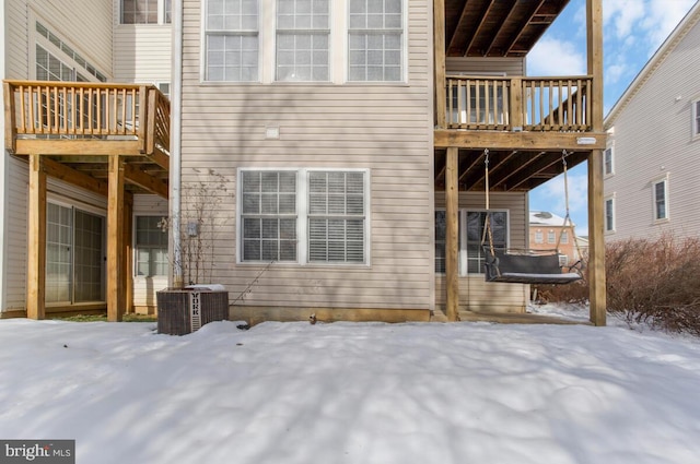 snow covered rear of property with central AC unit