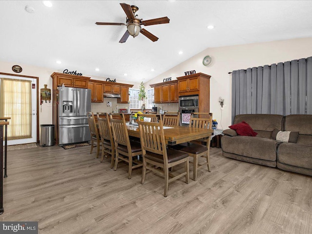 dining space featuring ceiling fan, light wood-type flooring, and vaulted ceiling