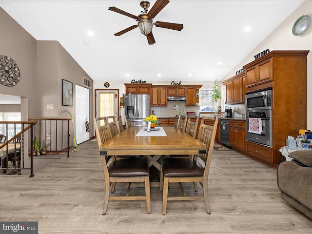 dining space featuring ceiling fan, vaulted ceiling, and light hardwood / wood-style flooring