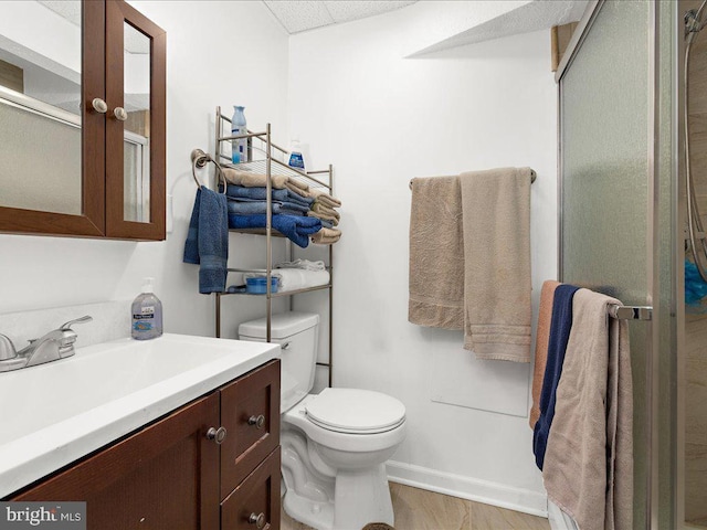 bathroom with toilet, vanity, and a shower with shower door