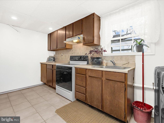 kitchen featuring white range with electric stovetop, washer / clothes dryer, decorative backsplash, sink, and light tile patterned floors