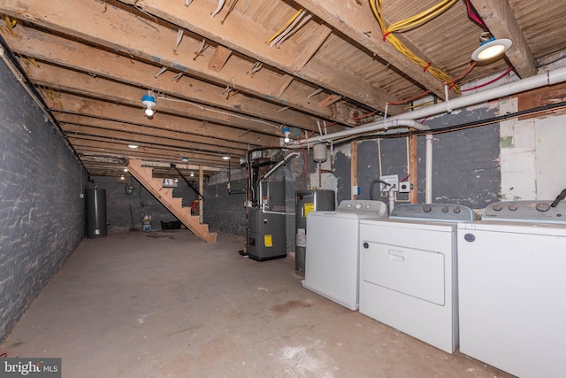 basement featuring washing machine and clothes dryer, heating unit, electric water heater, and water heater