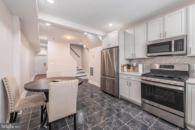 kitchen featuring white cabinets, appliances with stainless steel finishes, and decorative backsplash