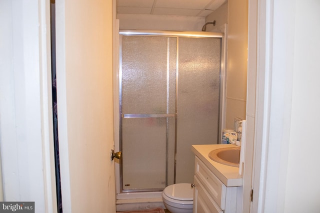 bathroom featuring vanity, toilet, walk in shower, and a drop ceiling