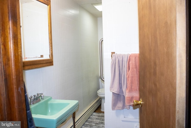 bathroom featuring hardwood / wood-style floors, sink, toilet, baseboard heating, and tile walls