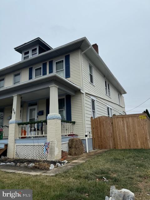 view of side of property featuring covered porch and a yard