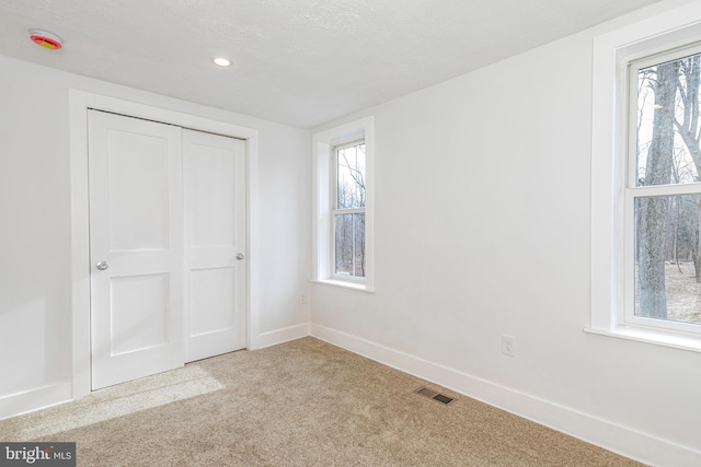 unfurnished bedroom featuring a textured ceiling and light colored carpet