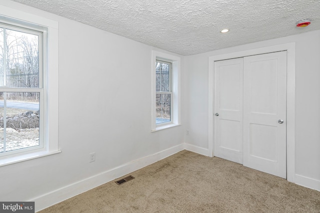 unfurnished bedroom with a textured ceiling and light colored carpet