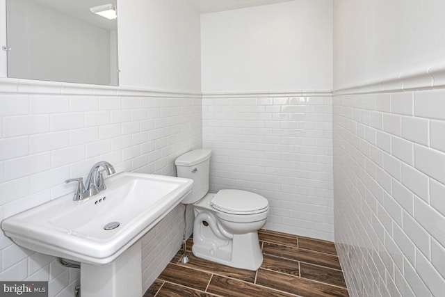 bathroom with sink, toilet, and tile walls