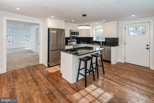 kitchen with white cabinetry, hanging light fixtures, appliances with stainless steel finishes, and a kitchen island