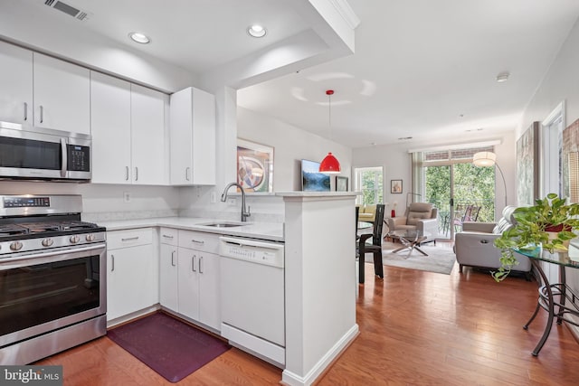 kitchen featuring sink, white cabinets, kitchen peninsula, and appliances with stainless steel finishes