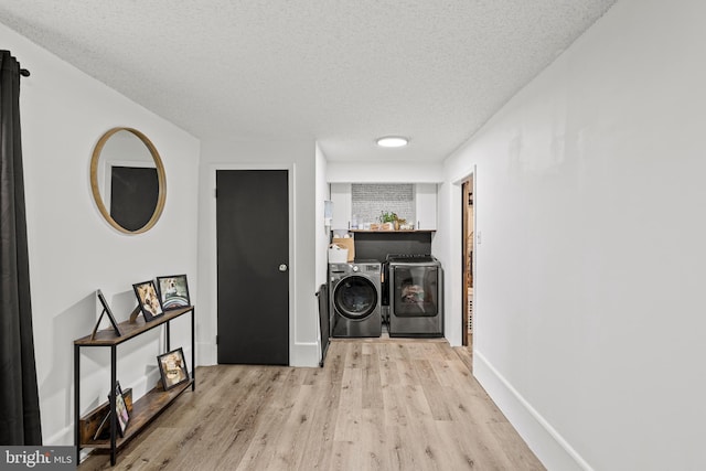 hallway with washer and dryer, light wood-type flooring, and a textured ceiling