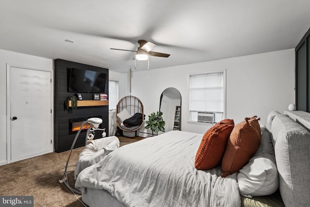 carpeted bedroom with ceiling fan, a fireplace, cooling unit, and a baseboard heating unit