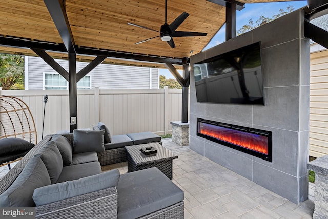 view of patio / terrace with an outdoor living space with a fireplace and ceiling fan