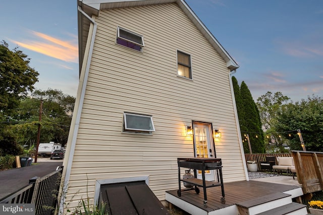 back house at dusk with a wooden deck