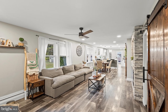 living room with a barn door, ceiling fan, a baseboard heating unit, and hardwood / wood-style flooring