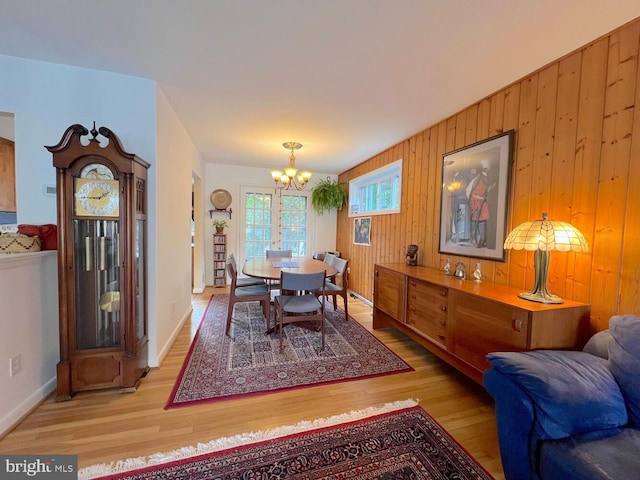 dining room with hardwood / wood-style floors, a notable chandelier, and wood walls