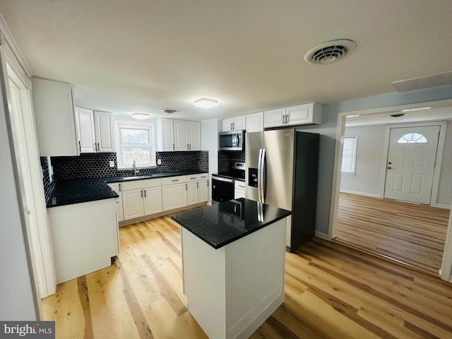 kitchen with a center island, white cabinets, light hardwood / wood-style floors, and appliances with stainless steel finishes