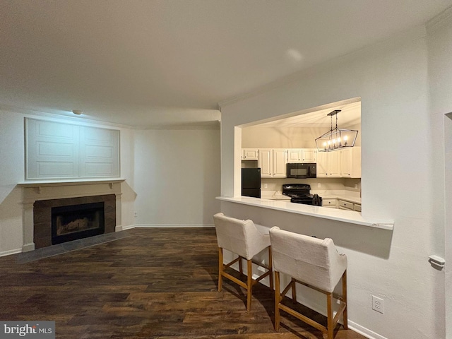 kitchen with black appliances, hanging light fixtures, kitchen peninsula, dark wood-type flooring, and white cabinets