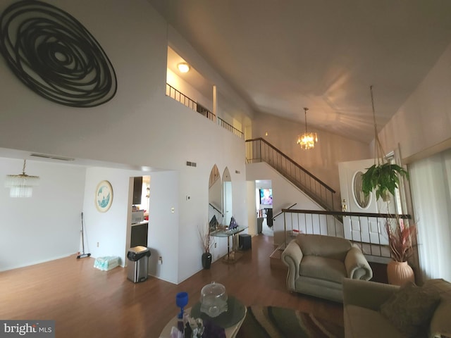 living room featuring hardwood / wood-style floors, a chandelier, and vaulted ceiling