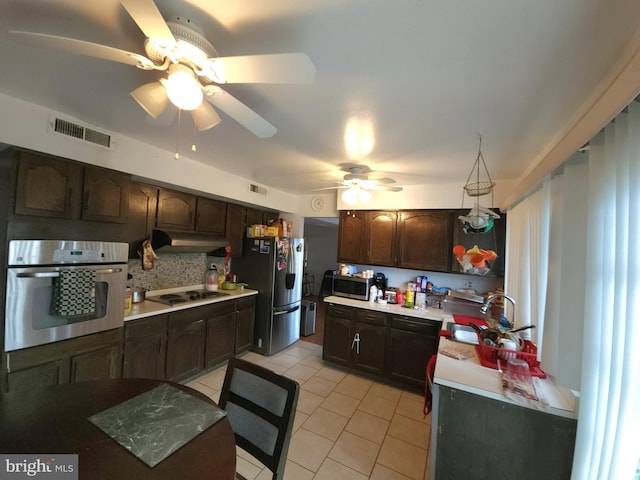 kitchen featuring dark brown cabinetry, sink, backsplash, light tile patterned floors, and appliances with stainless steel finishes