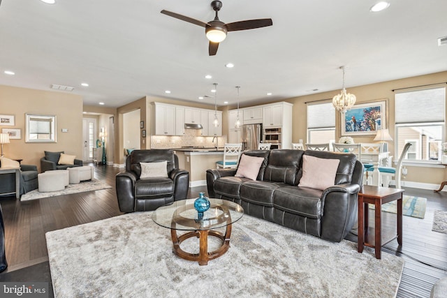 living room with hardwood / wood-style floors and ceiling fan with notable chandelier