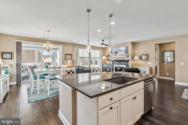 kitchen with pendant lighting, dishwasher, a center island with sink, white cabinets, and sink