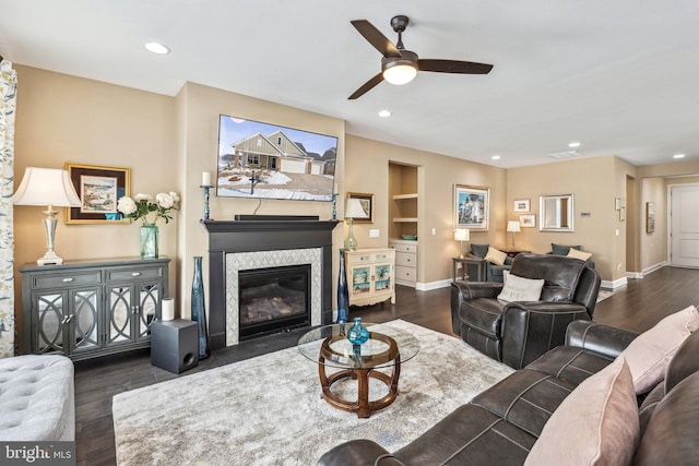 living room with built in shelves, ceiling fan, and dark hardwood / wood-style flooring