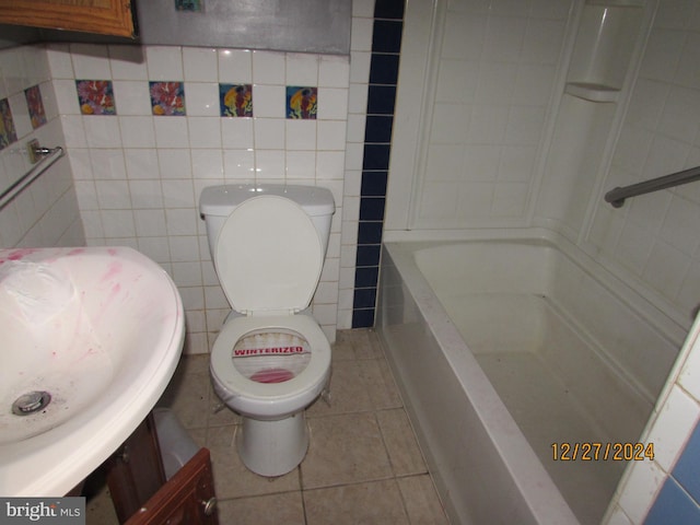 bathroom with a bathing tub, sink, tile patterned flooring, toilet, and tile walls