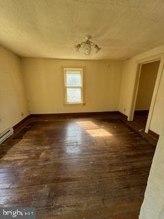 spare room featuring dark hardwood / wood-style flooring and a baseboard radiator