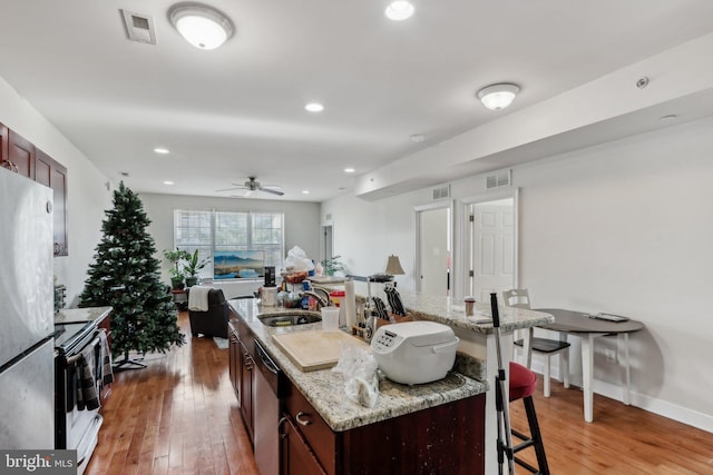 kitchen with an island with sink, stainless steel appliances, sink, and a breakfast bar area