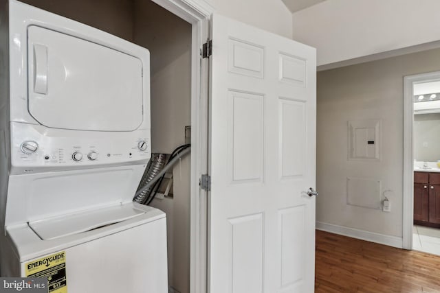 washroom with stacked washing maching and dryer, dark wood-type flooring, sink, and electric panel