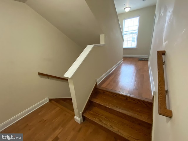 staircase featuring hardwood / wood-style flooring and lofted ceiling