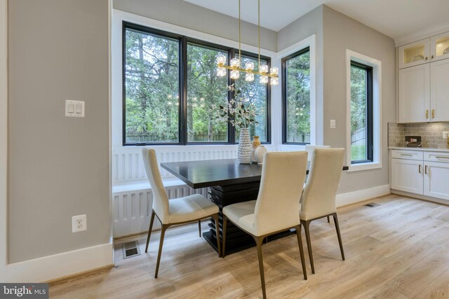 dining room featuring a chandelier, baseboards, light wood finished floors, and visible vents