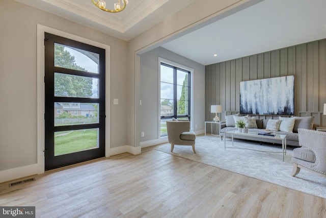 entrance foyer with visible vents, baseboards, ornamental molding, light wood-type flooring, and a notable chandelier