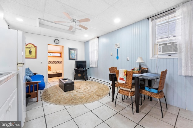 dining area featuring a drop ceiling, ceiling fan, light tile patterned flooring, and baseboard heating